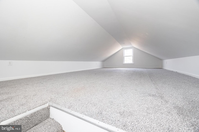 additional living space with carpet floors, vaulted ceiling, and baseboards