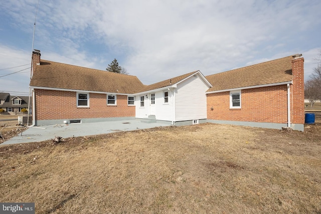 back of house with a patio area, a shingled roof, a chimney, and brick siding