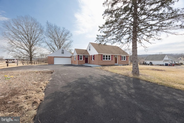 view of front facade with aphalt driveway, an outdoor structure, and brick siding