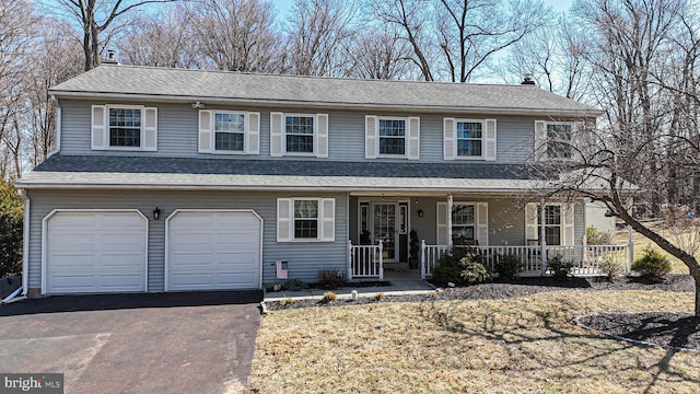 view of front of property featuring a shingled roof, aphalt driveway, a porch, a chimney, and a garage