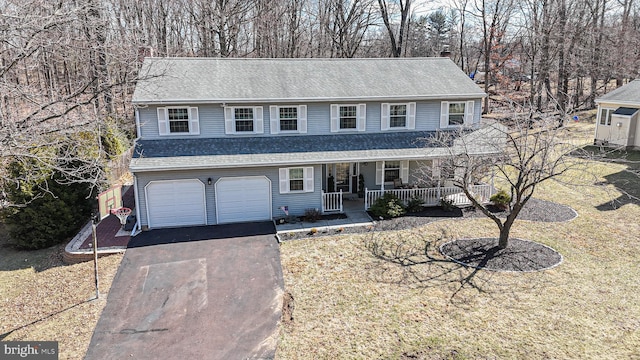 view of front of home featuring a front yard, driveway, a porch, a shingled roof, and a garage