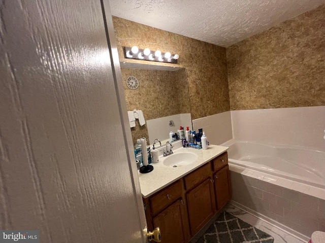 full bathroom with a textured ceiling, a garden tub, vanity, and wallpapered walls