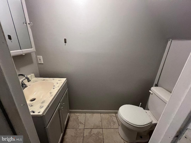 half bath with toilet, baseboards, and vanity