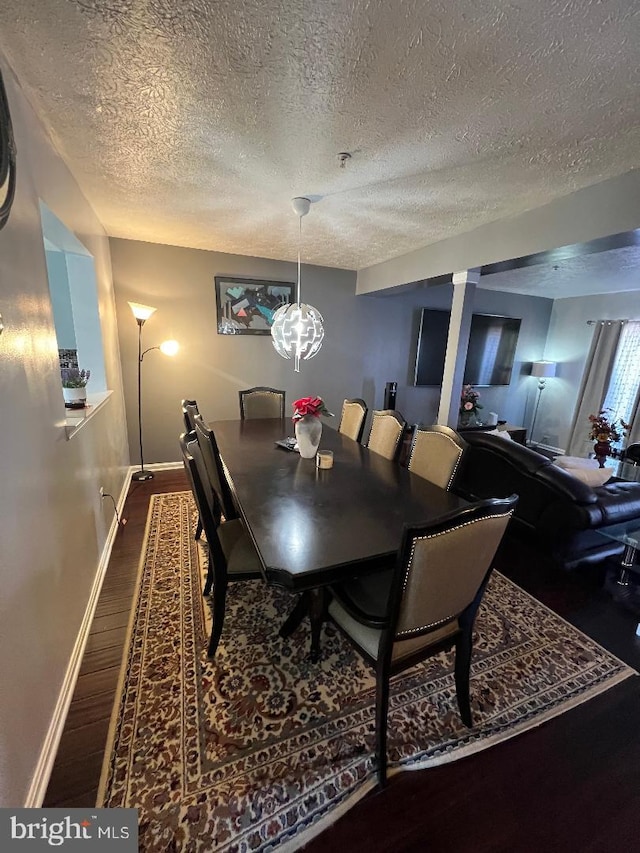 dining area with a textured ceiling, baseboards, and wood finished floors