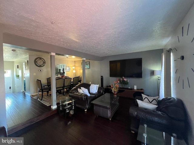 living area with decorative columns, a textured ceiling, baseboards, and hardwood / wood-style floors