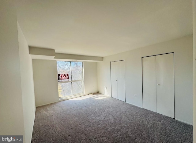 unfurnished bedroom with carpet and two closets