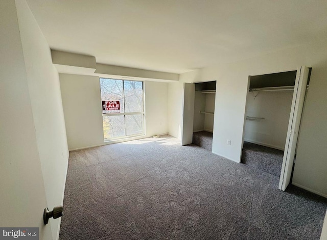 unfurnished bedroom with multiple closets and carpet flooring