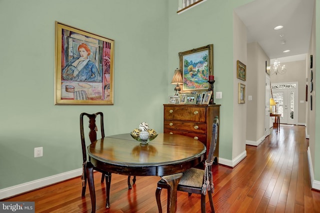 dining space with baseboards, an inviting chandelier, and hardwood / wood-style floors