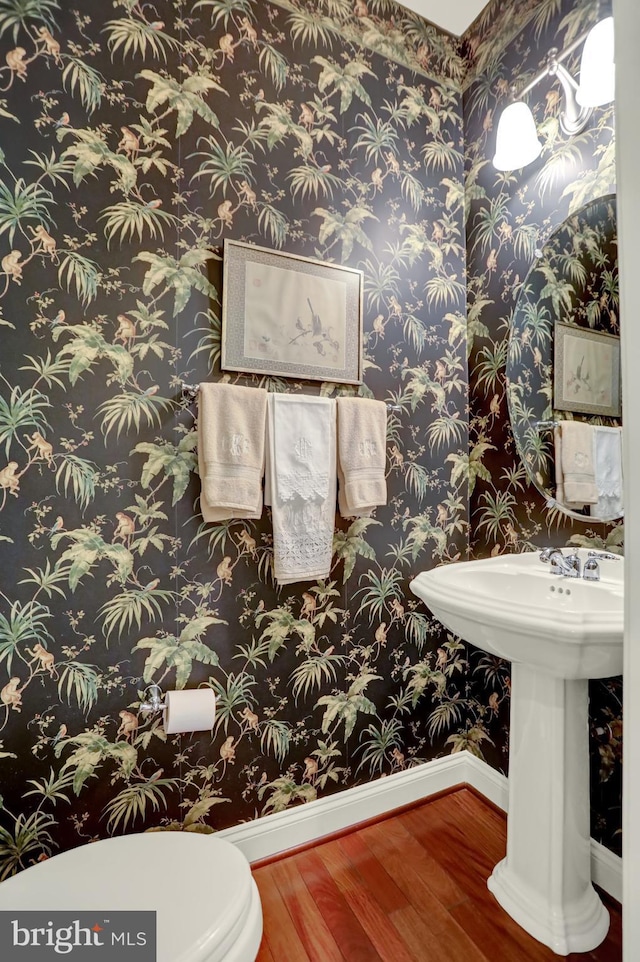 bathroom featuring a sink, toilet, baseboards, and wood finished floors