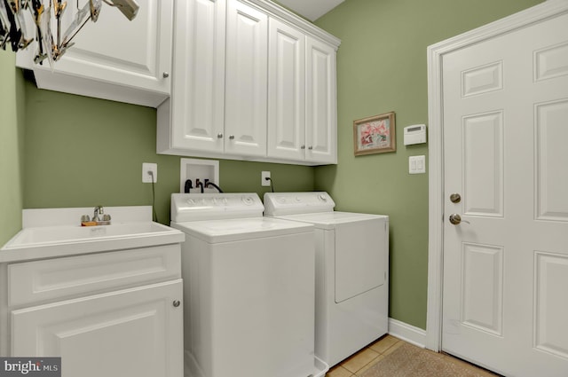 clothes washing area with baseboards, separate washer and dryer, light tile patterned flooring, cabinet space, and a sink