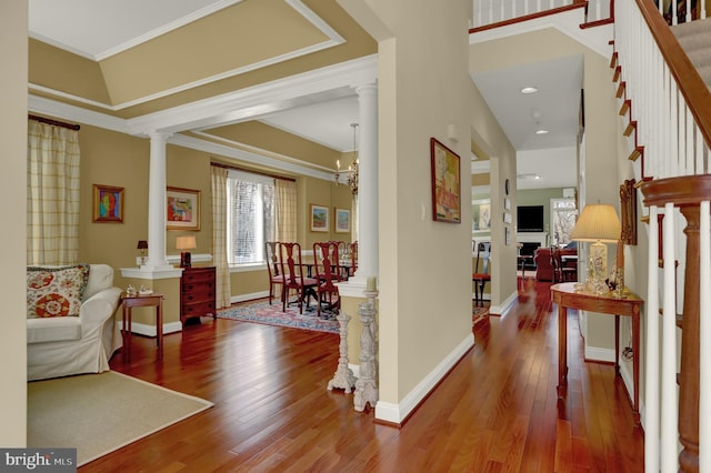 interior space featuring crown molding, decorative columns, baseboards, and wood-type flooring