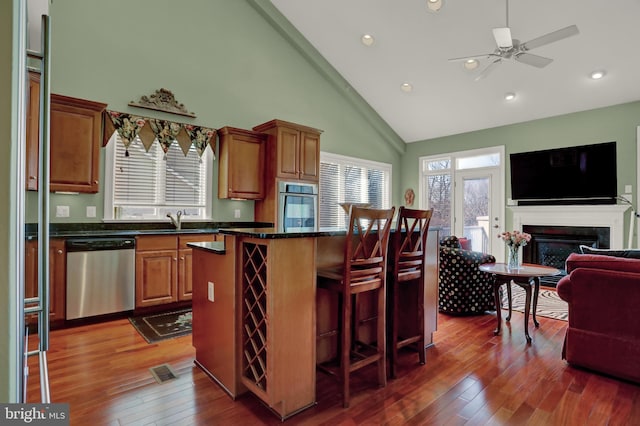 kitchen with a sink, a kitchen breakfast bar, open floor plan, stainless steel appliances, and a fireplace