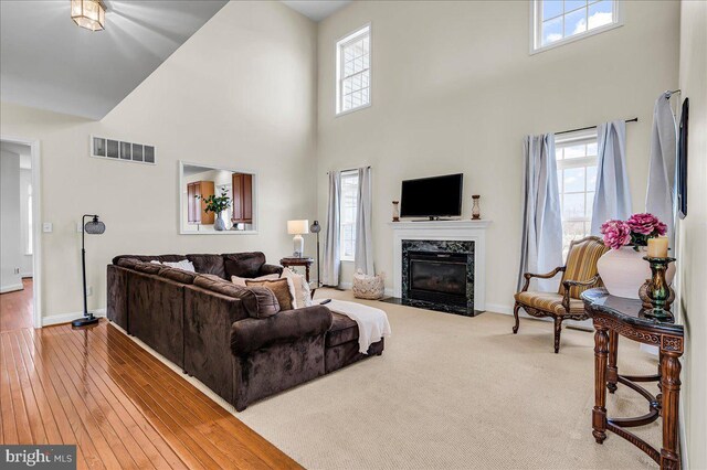 living area with visible vents, baseboards, a healthy amount of sunlight, and a premium fireplace