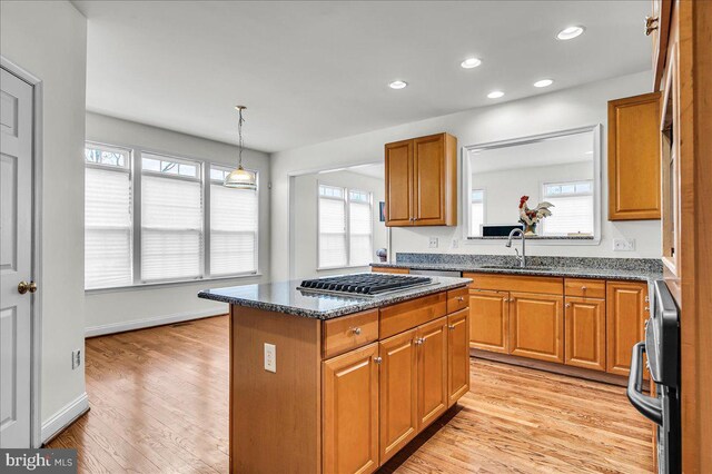 kitchen with brown cabinetry, stainless steel gas stovetop, a center island, and light wood finished floors