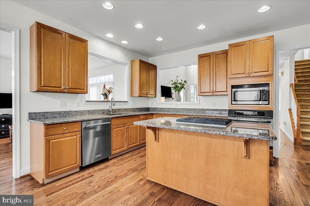 kitchen with a sink, a kitchen breakfast bar, a center island, appliances with stainless steel finishes, and light wood finished floors