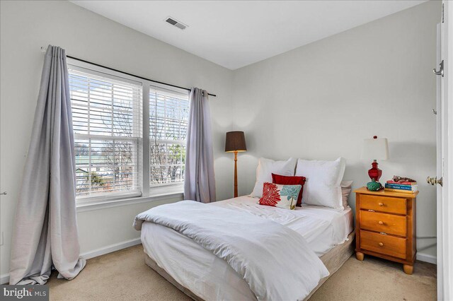 bedroom with visible vents, light colored carpet, and baseboards