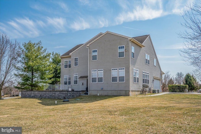 back of house with a yard, driveway, central AC, and a garage