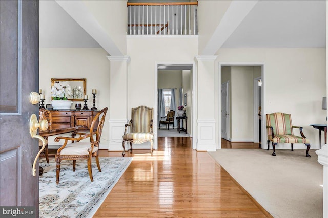 foyer entrance with decorative columns, a high ceiling, and wood finished floors