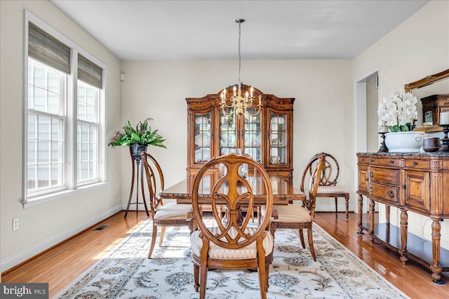 dining room with light wood finished floors, baseboards, and an inviting chandelier