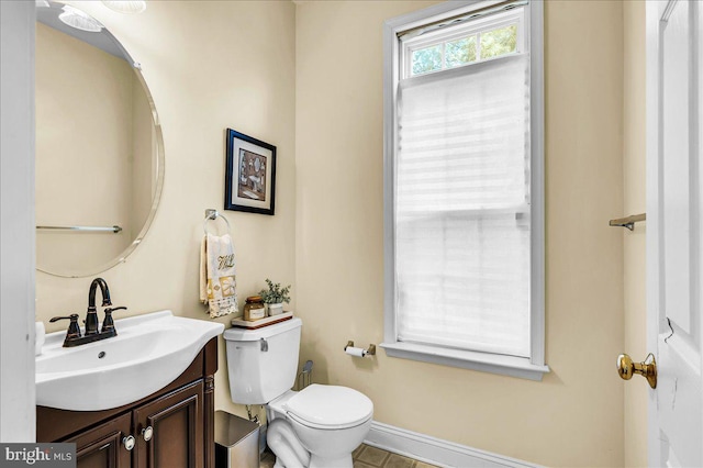 bathroom with toilet, vanity, and baseboards