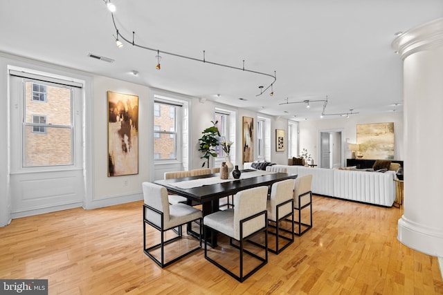 dining area with light wood-style flooring, rail lighting, visible vents, and ornate columns