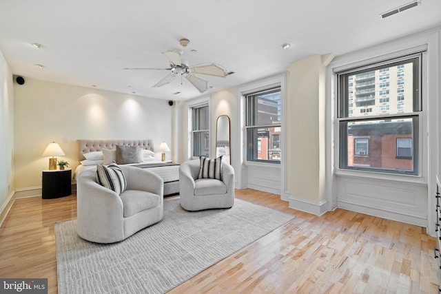 bedroom with light wood-style flooring, multiple windows, visible vents, and ceiling fan