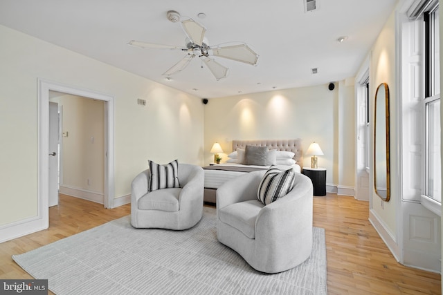 bedroom featuring a ceiling fan, visible vents, light wood-style flooring, and baseboards