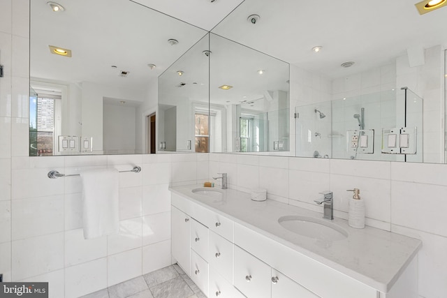 full bath with a stall shower, a sink, tile walls, and double vanity