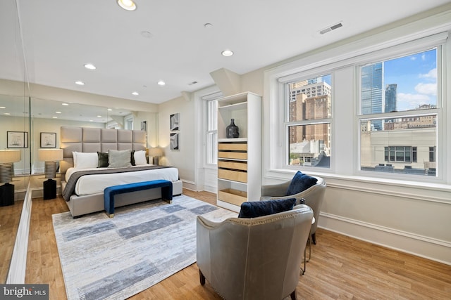 bedroom with baseboards, wood finished floors, visible vents, and recessed lighting