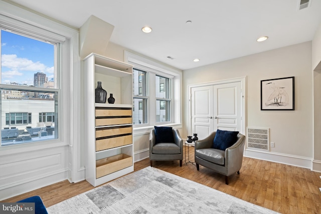 living area featuring plenty of natural light, visible vents, and wood finished floors