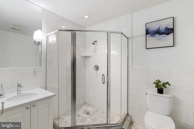 bathroom featuring a stall shower, tile walls, and toilet