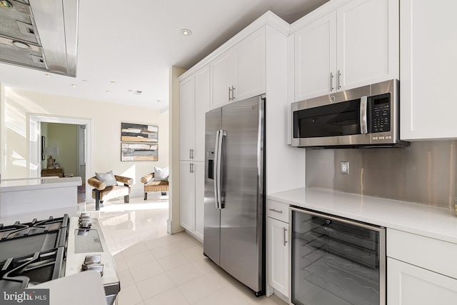 kitchen featuring light tile patterned floors, wine cooler, white cabinetry, light countertops, and appliances with stainless steel finishes