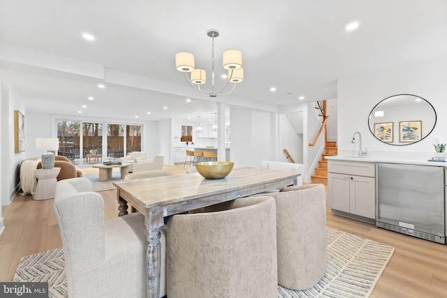 dining space with a notable chandelier, stairway, recessed lighting, and light wood-style floors