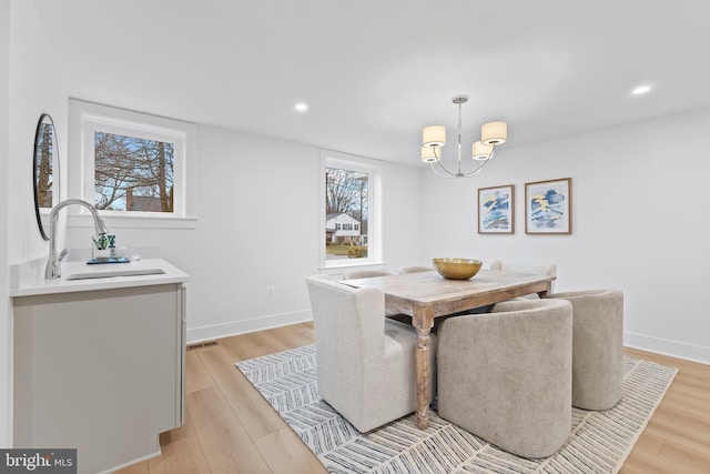 dining space with light wood-style flooring, baseboards, and an inviting chandelier