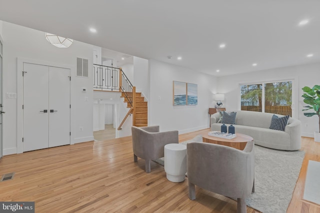 living room with light wood-type flooring, visible vents, recessed lighting, and stairs