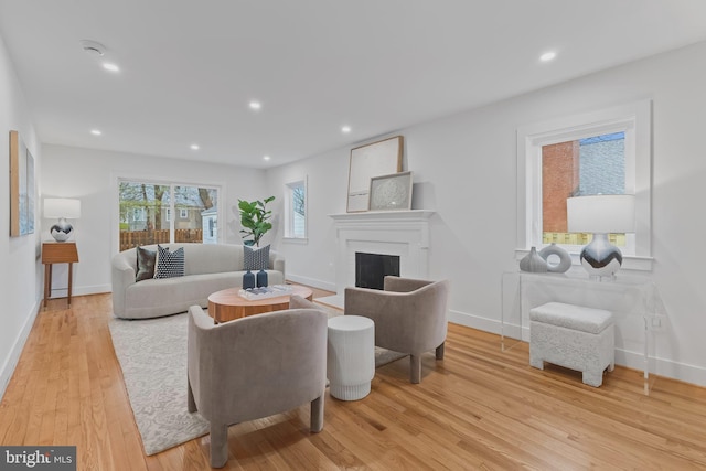 living area featuring light wood-type flooring, a fireplace, baseboards, and recessed lighting