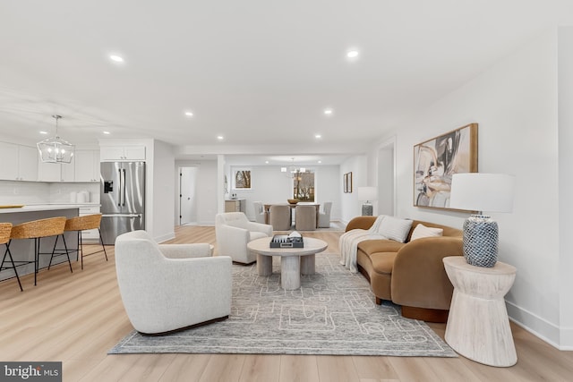 living room featuring light wood finished floors, baseboards, a chandelier, and recessed lighting