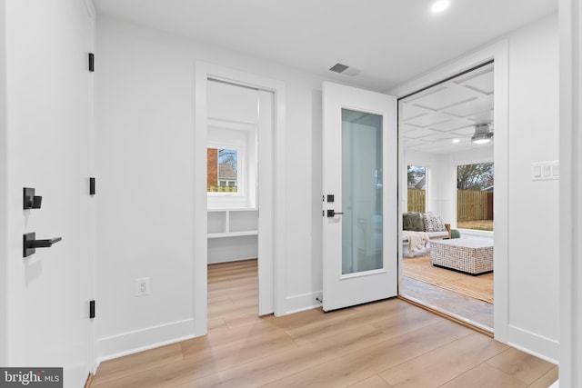 interior space with light wood-type flooring, visible vents, and baseboards