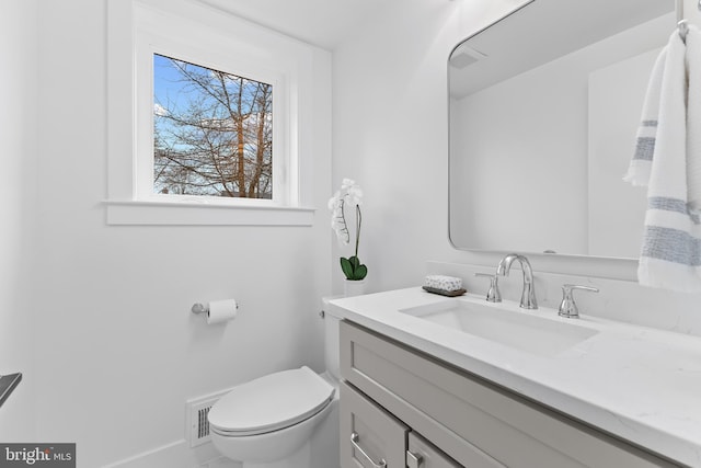 bathroom with baseboards, vanity, and toilet