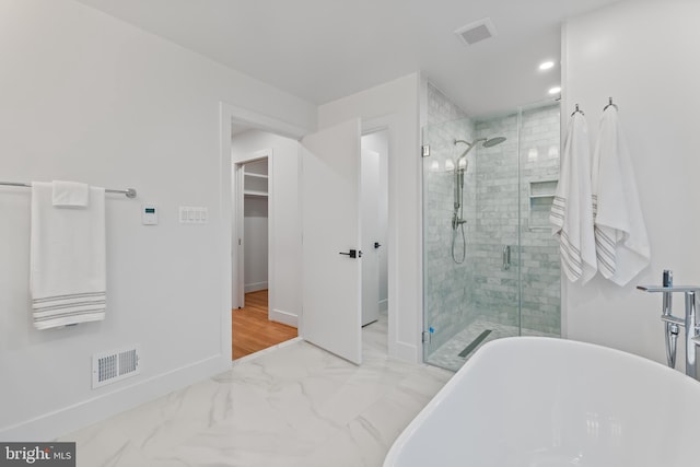 full bath with a freestanding tub, a shower stall, visible vents, and baseboards