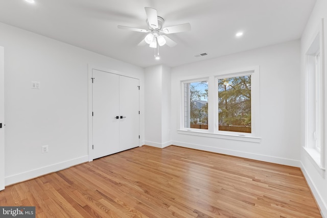 empty room with baseboards, ceiling fan, visible vents, and light wood-style floors