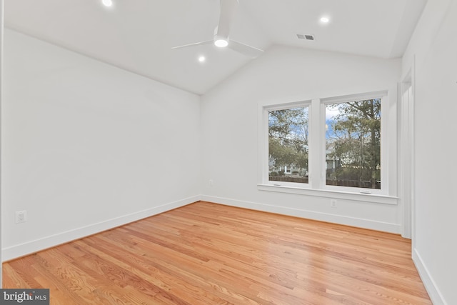 spare room with light wood-type flooring, visible vents, lofted ceiling, and baseboards