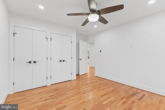 unfurnished bedroom featuring baseboards, recessed lighting, two closets, and light wood-style floors