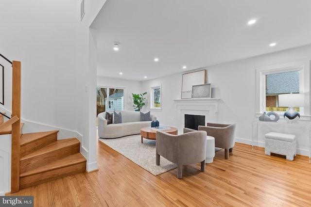 living room with light wood finished floors, plenty of natural light, stairway, a fireplace, and recessed lighting