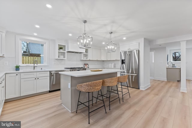 kitchen featuring white cabinets, appliances with stainless steel finishes, a breakfast bar, a center island, and a sink