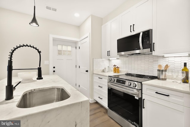 kitchen with visible vents, appliances with stainless steel finishes, white cabinets, and a sink