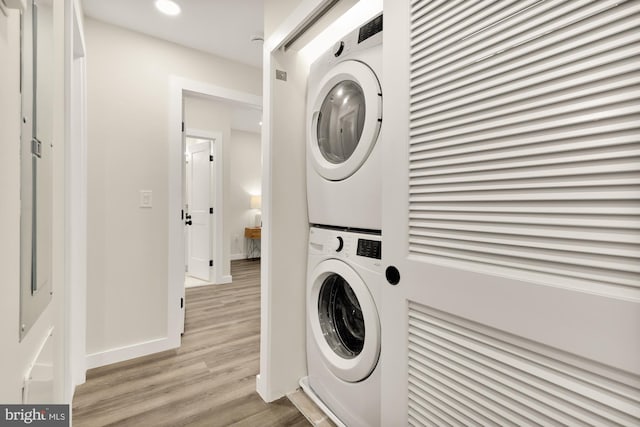 laundry room with recessed lighting, stacked washer and dryer, laundry area, baseboards, and light wood-type flooring