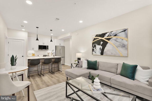 living room with visible vents, light wood-style flooring, and recessed lighting