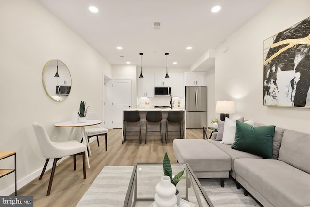 living area with light wood-style flooring, visible vents, baseboards, and recessed lighting