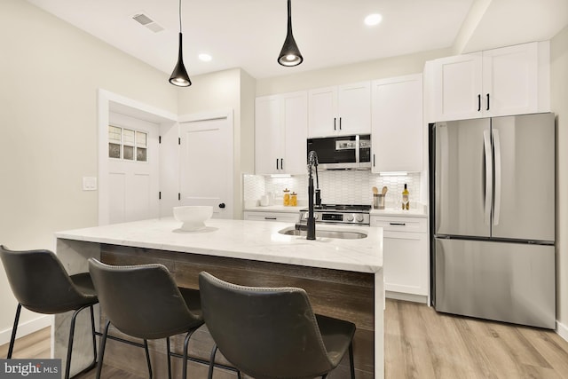 kitchen featuring tasteful backsplash, appliances with stainless steel finishes, visible vents, and white cabinets